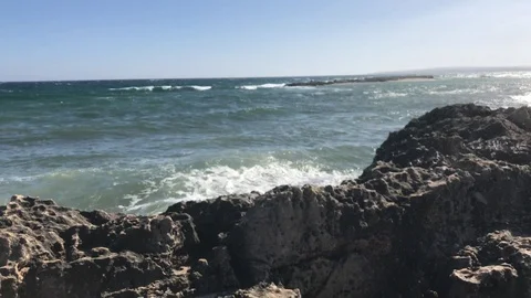 Tracking Shot at the beach with waves splashing at the cliffs Stock Footage 90412328