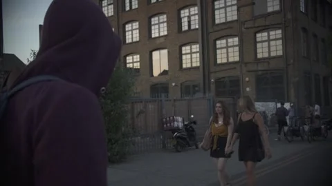 Tracking Shot Behind Hooded Man Walking Down Urban Street 库存影片 344625739