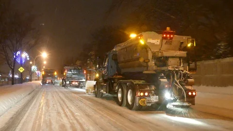 Tracking shot behind snow clearing operation at night with salt dispenser Stock Footage 101218422