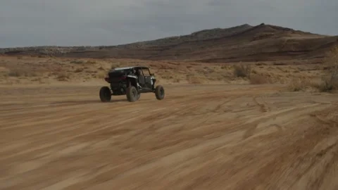 Tracking shot behind UTV driving in sunny Utah desert landscape in sand wash Stock Footage 234036855