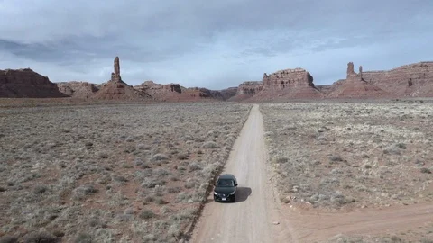 Tracking shot of black car driving by two bicyclists on beautiful desert road Stock Footage 124879112