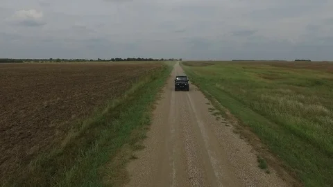 Tracking shot with a black SUV driving down a dirt road Stock Footage 81722325