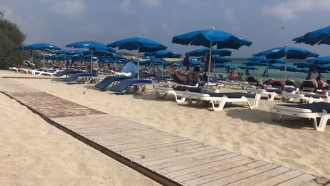 Tracking Shot of Blue Sun Beds and Umbrellas on a Windy Cloudy Stock-Footage 101248836