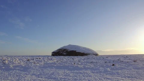Tracking shot camera moves in volcanic landscape covered snow around big rock Stock Footage 94134067