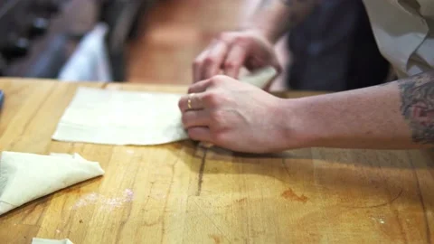 Tracking shot of a chef wrapping triangular parcels ready to cook Stock Footage 234257544