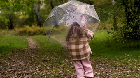 Tracking shot of child with umbrella walking through forest path in autumn Stock Footage 346622435
