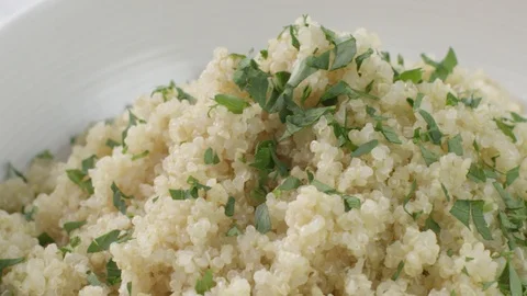 Tracking shot Chopped fresh herbs being sprinkled onto a bowl of cooked quinoa Stock-Footage 87720600
