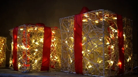 Tracking shot of Christmas present decorations lit up against a dark backdrop Stock Footage 106810716