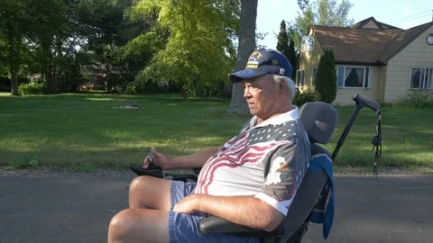 Tracking shot of a disabled war veteran in a powered wheelchair Vídeos de archivo 93592833