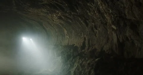 Tracking shot of explorers hiking through smoky cave towards camera Stock Footage 64684650