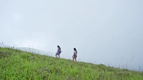 A tracking shot follows two young Indian girls climbing to a mountain peak .. Stock Footage 313381114
