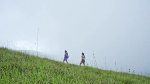 A tracking shot follows two young Indian girls climbing to a mountain peak .. 스톡 동영상 313381118