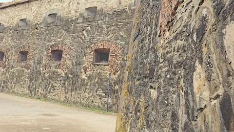 Tracking shot gliding along a massive historic stone fortress wall with bar.. Stock Footage 346656683