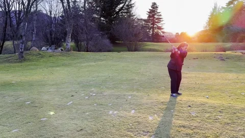 Tracking Shot on a Golfer with Hitting the Golf Ball on the Fairway in Sunset Video stock 267734402