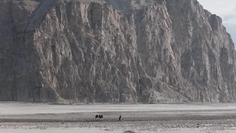 Tracking shot of a group walking across a vast desert landscape towards a 스톡 동영상 317957833