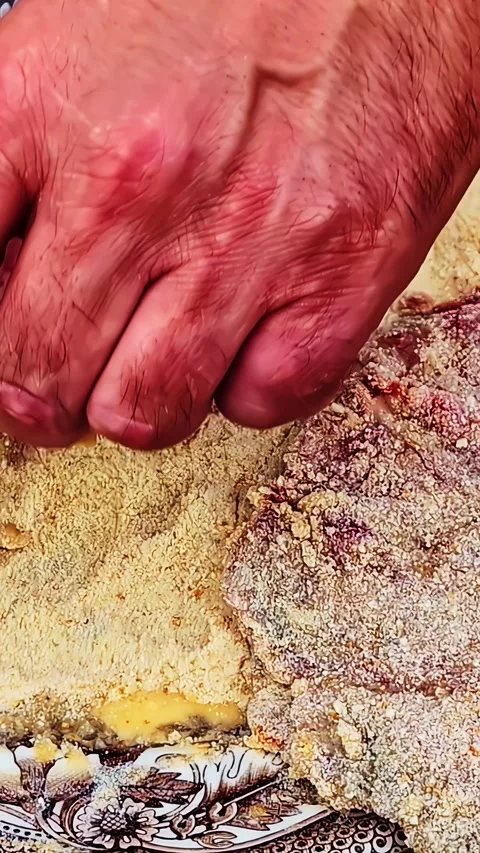 Tracking Shot of Hand Dipping Raw Steak in Egg Before Breading Portraying Stock Footage 339031744