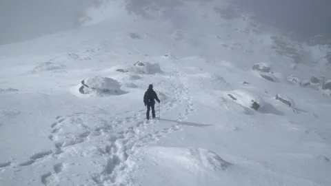 Tracking shot of hiker approaching the summit of the snowy mountain peak Stock Footage 86612289