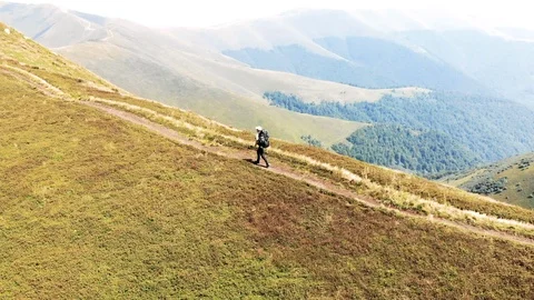 Tracking shot of hiker walking on mountain trail Drone shot of young man hiking Stock Footage 102464680
