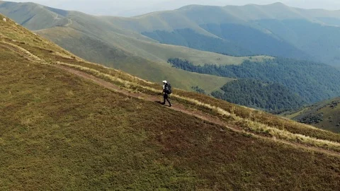 Tracking shot of hiker walking on mountain trail Drone shot of young man hiking Stock Footage 102464911