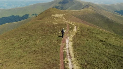 Tracking shot of hiker walking on mountain trail Drone shot of young man hiking Stock Footage 102465694
