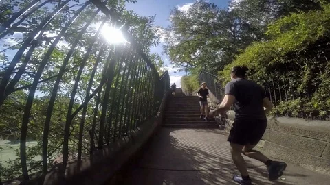 Tracking shot of joggers running up steps in slow motion. Vídeo Stock 89854635