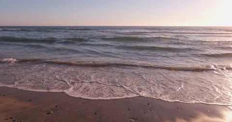 Tracking shot from left to right along shoreline of beach at sunset 스톡 동영상 135371701