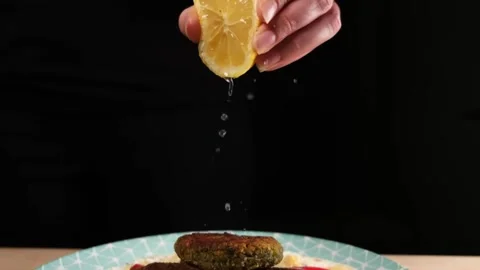 Tracking shot of lemon juice squeeze on plate with food, slow motion. Video stock 154713222