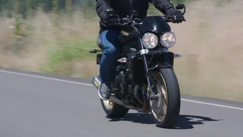 Tracking shot of man riding motorcycle on country road.  Fully released for Stock Footage