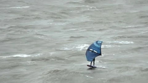 Tracking shot of a man riding a wingboard in the middle of big Atlantic waves Stock Footage 230892687