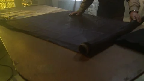 A tracking shot of a man rolling out a piece of fabric Stock Footage 311924054