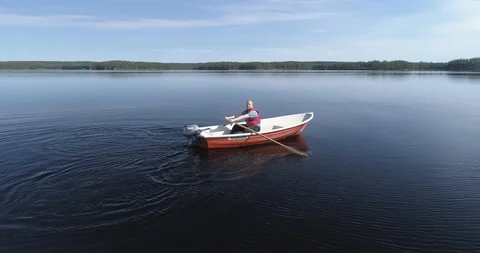 Tracking Shot of a Man Rowing a Boat in a Tranquil Forest Lake During Summer Stock Footage 85886274