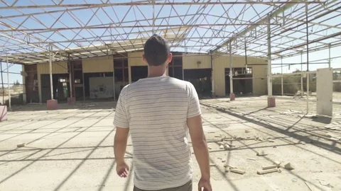 Tracking shot of a man walking in an abandoned factory Stock Footage 81857124