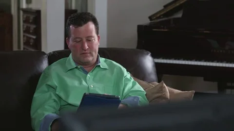 Tracking shot of man working from his living room on his tablet Stock Footage 71343516