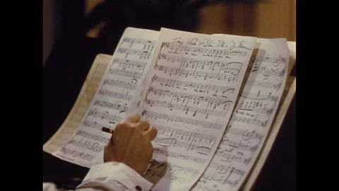 Tracking shot of man writing on sheet music at piano, 1940s Stock Footage