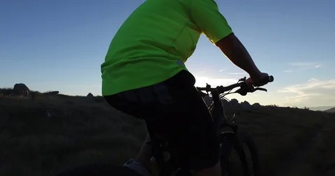 Tracking shot: Mountain biker riding at sunset Stock Footage 82357532
