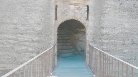 Tracking shot moving into a stairwell through a stone archway of an old fort Stock Footage 88903530
