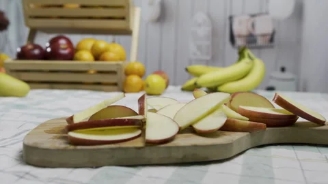 Tracking shot near red apple slices on wooden cutting board in kitchen - closeup Stock Footage 341188880