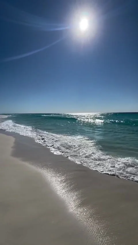 Tracking shot ocean waves crashing on sunny sandy beach with lens flare Vídeos de archivo 333605301