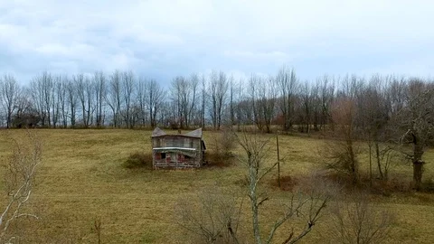 Tracking in shot of old abandoned crumbling farmhouse in middle of pasture Stock Footage 100416585