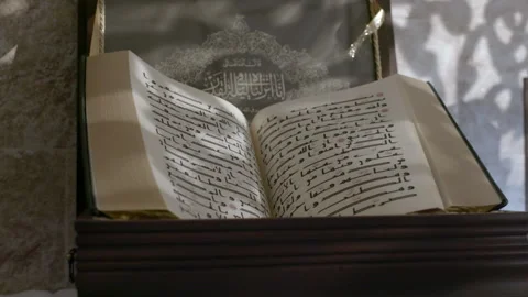 Tracking shot of an opened Quran written in old Kufi font. Quran is the Stock Footage 220774141