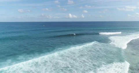 Tracking shot over surfers catching waves or surf on surfing at wild tropical Stock Footage 131739644