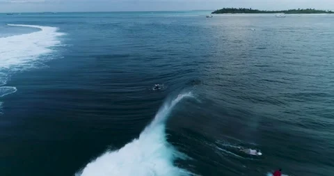 Tracking shot over surfers catching waves or surf on surfing at wild tropical Stock Footage 131739732