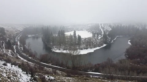 Tracking shot over train track and river toward snow covered inlet with trees Stock Footage 124616216