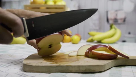 Tracking shot of person cutting apple into slices with sharp knife on cutting Stock Footage 341230462
