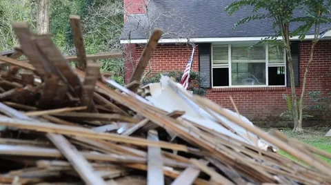 Tracking Shot of Pile of Lumber in Foreground of Flood Damaged House Stock-Footage 67834998