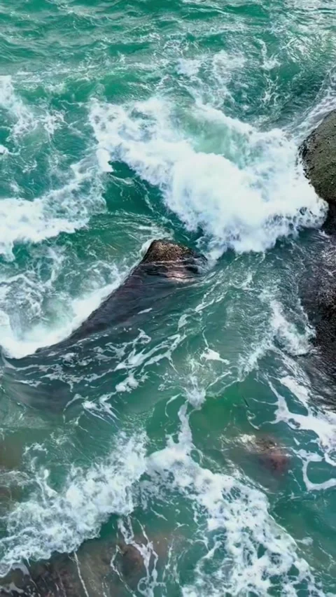 Tracking shot powerful ocean waves crashing against rocky cliffs in turquoise Vidéo 333605278