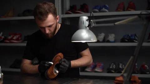 Tracking shot of professional shoemaker wearing black gloves polishing old light Stock Footage 150069921