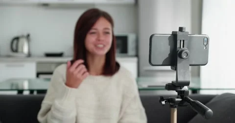 Tracking shot with rack focus of young female video blogger in a sweater talking Stock Footage 171292302
