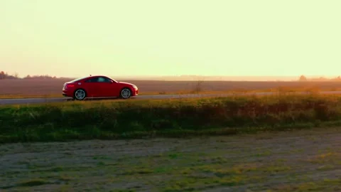Tracking shot of a red Audi car riding on an empty countryside road. Video stock 242988515