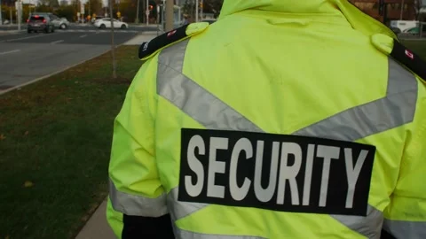 Tracking shot of security guard in uniform patrolling commercial area. Stock Footage 153888503